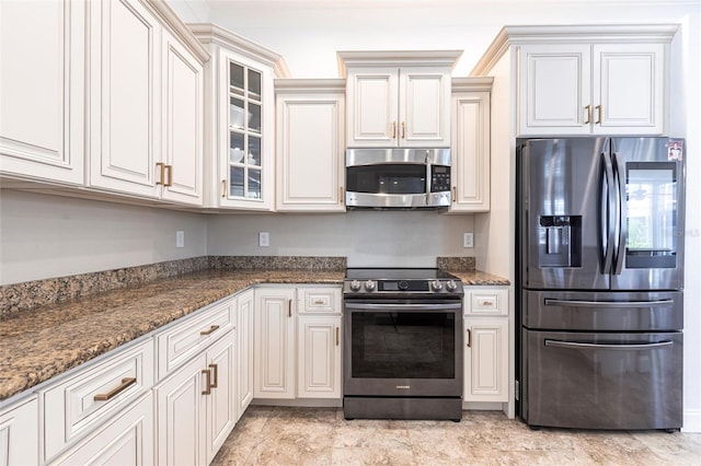 kitchen featuring dark stone countertops, appliances with stainless steel finishes, and glass insert cabinets