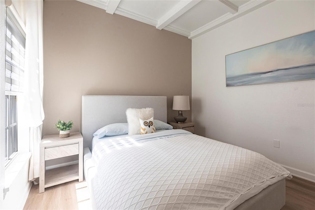 bedroom with baseboards, beamed ceiling, and wood finished floors