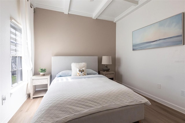 bedroom featuring baseboards, beamed ceiling, multiple windows, and wood finished floors