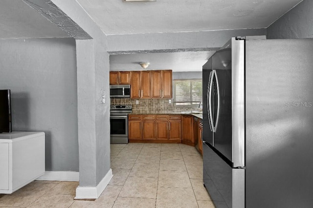 2026 Cocoanut Ave, Sarasota, FL 34234 - kitchen with light tile patterned floors, brown cabinets, a sink, appliances with stainless steel finishes, and tasteful backsplash