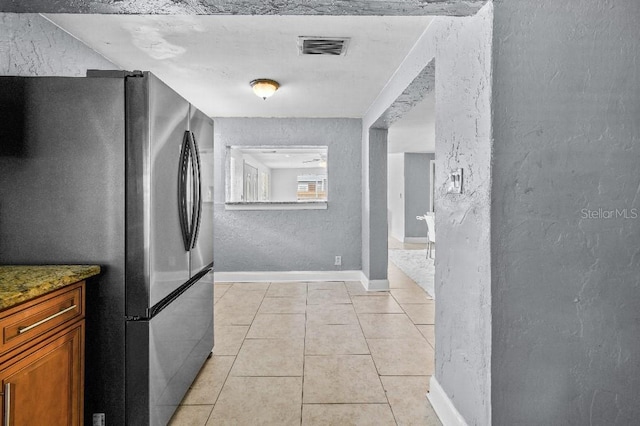 2026 Cocoanut Ave, Sarasota, FL 34234 - interior space featuring brown cabinetry, freestanding refrigerator, visible vents, a textured wall, and light tile patterned floors