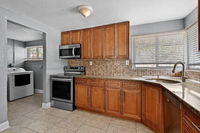 2026 Cocoanut Ave, Sarasota, FL 34234 - kitchen with a sink, brown cabinetry, backsplash, appliances with stainless steel finishes, and washer / clothes dryer