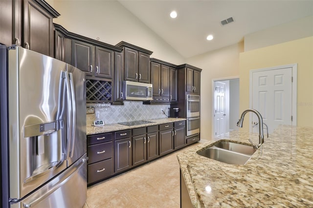 kitchen with dark brown cabinetry, backsplash, visible vents, appliances with stainless steel finishes, and a sink