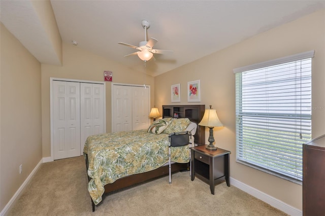 bedroom featuring multiple windows, light carpet, and two closets