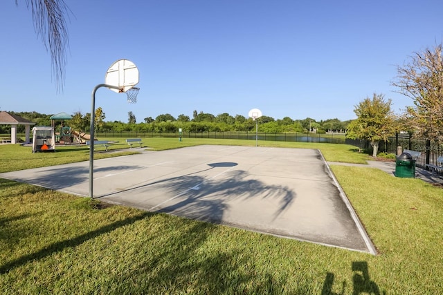 view of sport court featuring fence, community basketball court, a water view, and a yard