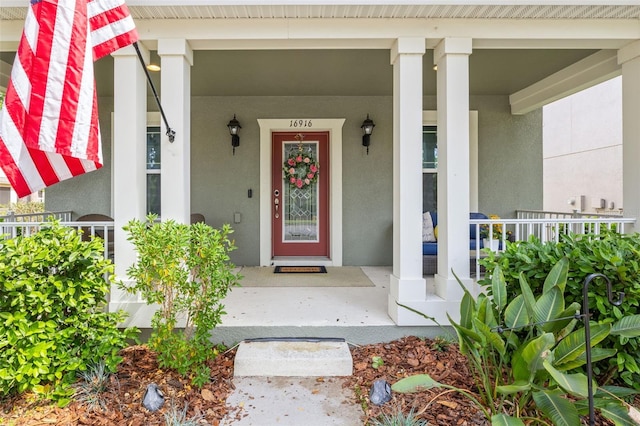 entrance to property featuring a porch and stucco siding