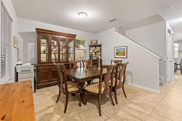 dining room with visible vents, baseboards, stairway, a textured ceiling, and light tile patterned floors
