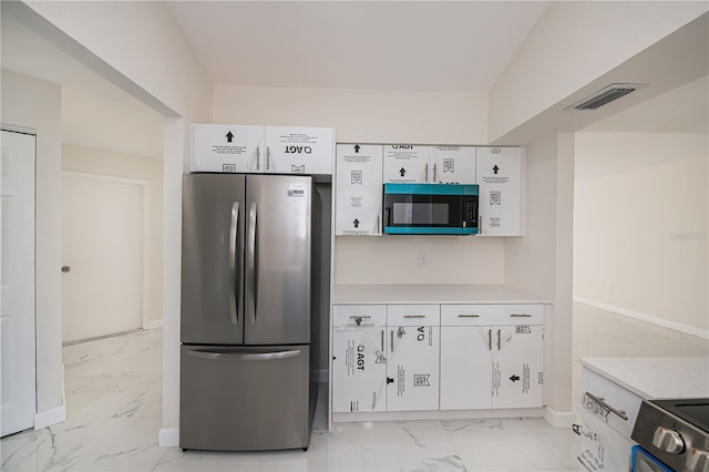 2167 Corfell St, Port Charlotte, FL 33948 - kitchen with freestanding refrigerator, light marble finish flooring, white cabinetry, light countertops, and range