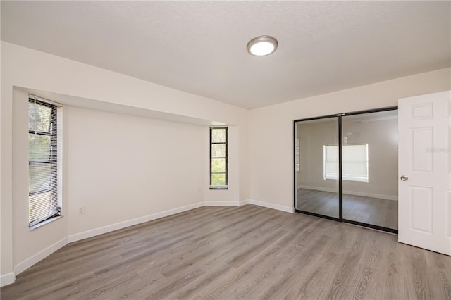 2167 Corfell St, Port Charlotte, FL 33948 - unfurnished bedroom with light wood-style flooring, multiple windows, baseboards, and a closet