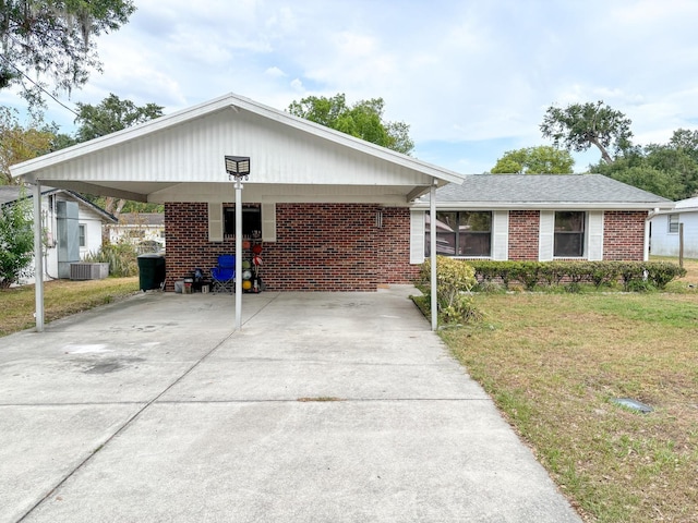ranch-style house with concrete driveway, cooling unit, a front lawn, and a carport