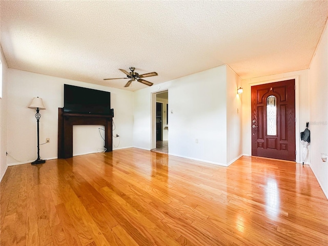 unfurnished living room with baseboards, a ceiling fan, a textured ceiling, and wood finished floors