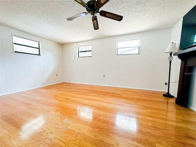 interior space featuring plenty of natural light, a textured ceiling, ceiling fan, and wood finished floors