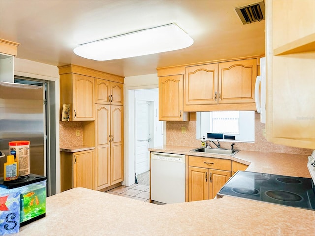 kitchen featuring visible vents, light brown cabinetry, white dishwasher, light countertops, and a sink
