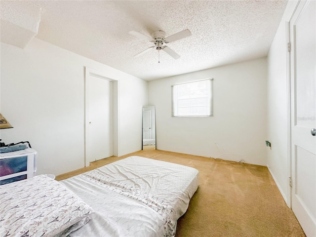 bedroom featuring ceiling fan, a textured ceiling, and light colored carpet