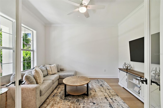 living area featuring ornamental molding, light wood finished floors, a ceiling fan, and baseboards