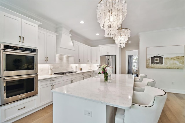 kitchen with stainless steel appliances, a chandelier, a center island, crown molding, and custom range hood