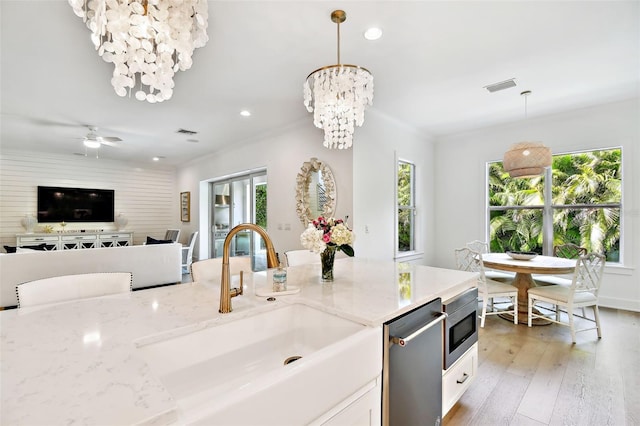 kitchen with a sink, stainless steel appliances, healthy amount of natural light, light stone countertops, and recessed lighting