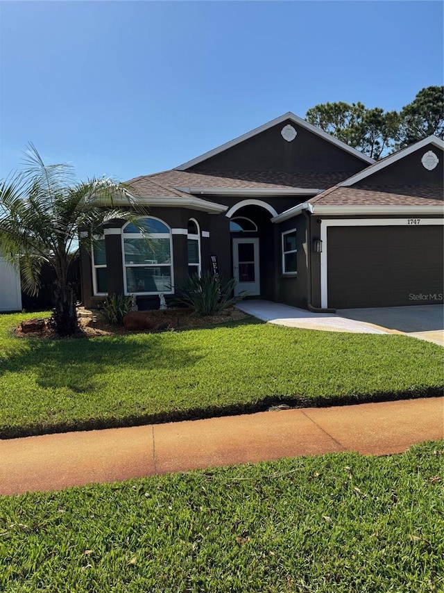 1747 Wood Brook St, Tarpon Springs, FL 34689 - ranch-style home featuring a shingled roof, an attached garage, driveway, a front lawn, and stucco siding