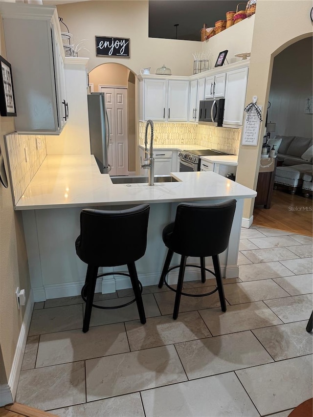 1747 Wood Brook St, Tarpon Springs, FL 34689 - kitchen featuring appliances with stainless steel finishes, a peninsula, a breakfast bar, and arched walkways