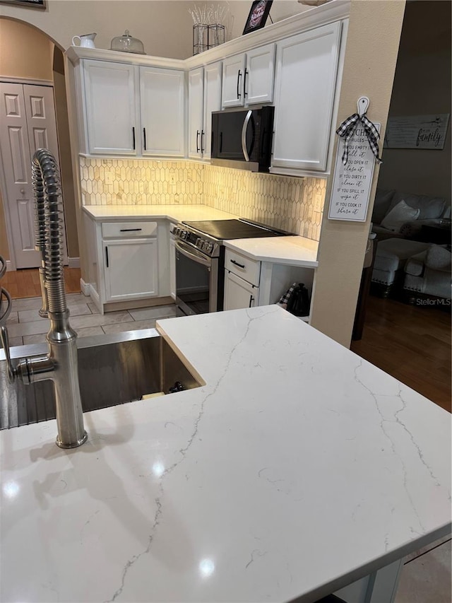1747 Wood Brook St, Tarpon Springs, FL 34689 - kitchen with stainless steel electric stove, a sink, backsplash, and white cabinets