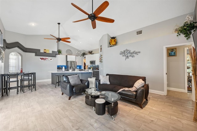 living room with high vaulted ceiling, a ceiling fan, baseboards, light wood-type flooring, and visible vents