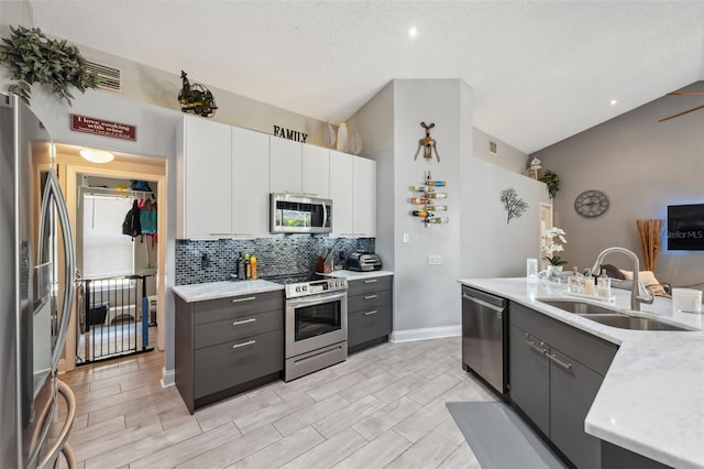 kitchen with a sink, appliances with stainless steel finishes, gray cabinets, and backsplash