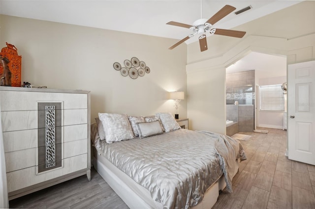 bedroom with a ceiling fan, ensuite bathroom, wood finished floors, lofted ceiling, and visible vents