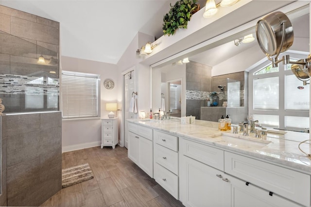 bathroom with a sink, walk in shower, vaulted ceiling, and double vanity