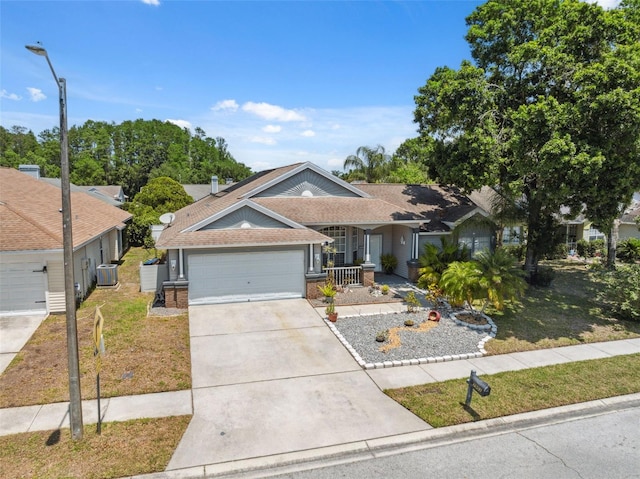 single story home with a porch, a garage, brick siding, cooling unit, and concrete driveway