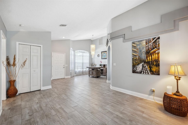 entryway with visible vents, baseboards, and vaulted ceiling