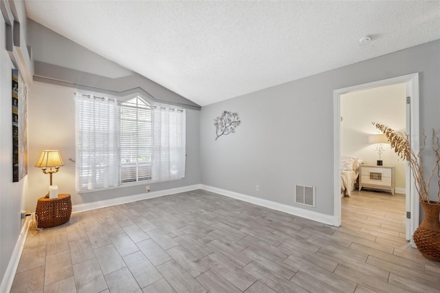 spare room with visible vents, lofted ceiling, and wood finished floors