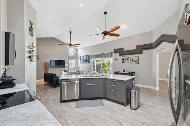 kitchen with ceiling fan, appliances with stainless steel finishes, a sink, open floor plan, and gray cabinetry