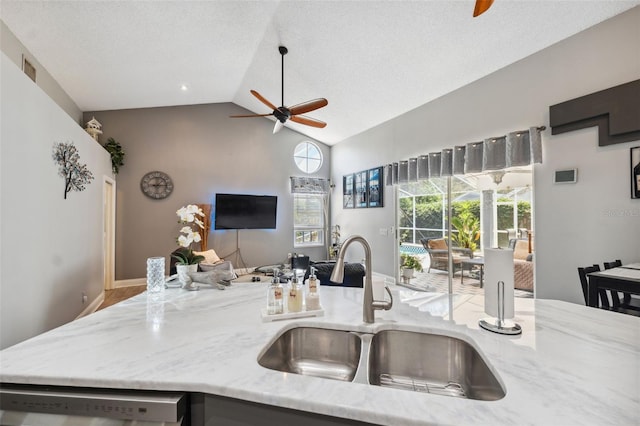kitchen with ceiling fan, high vaulted ceiling, light stone counters, a sink, and dishwasher