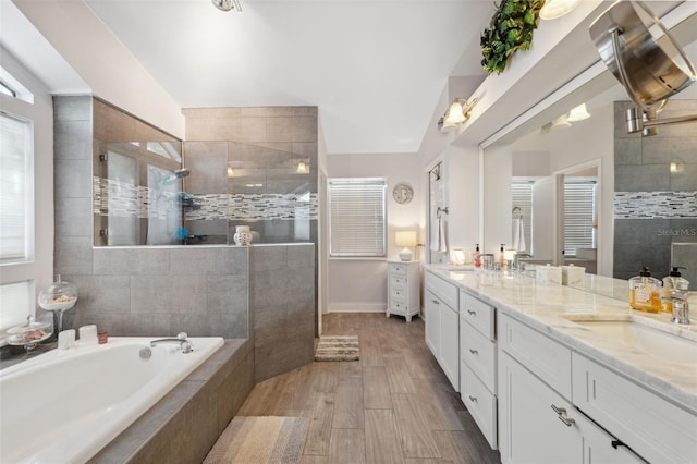 full bath with double vanity, a sink, a bath, and tiled shower