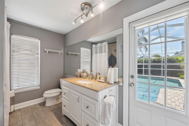 bathroom with toilet, baseboards, plenty of natural light, and vanity