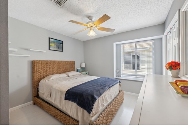 bedroom with baseboards, a ceiling fan, a textured ceiling, and visible vents