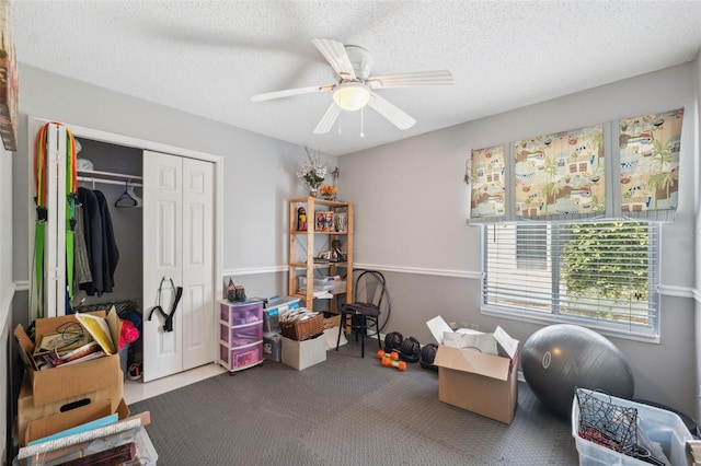 playroom featuring carpet flooring, a textured ceiling, and a ceiling fan