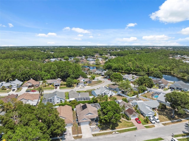 drone / aerial view featuring a wooded view, a water view, and a residential view