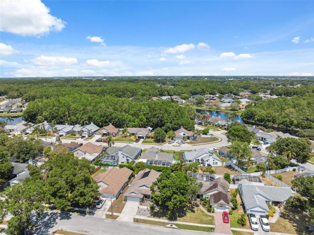 drone / aerial view with a wooded view, a water view, and a residential view
