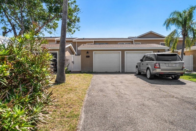829 E Gulf Blvd Unit 107, Indian Rocks Beach, FL 33785 - view of front of house with stucco siding, asphalt driveway, a garage, and roof with shingles