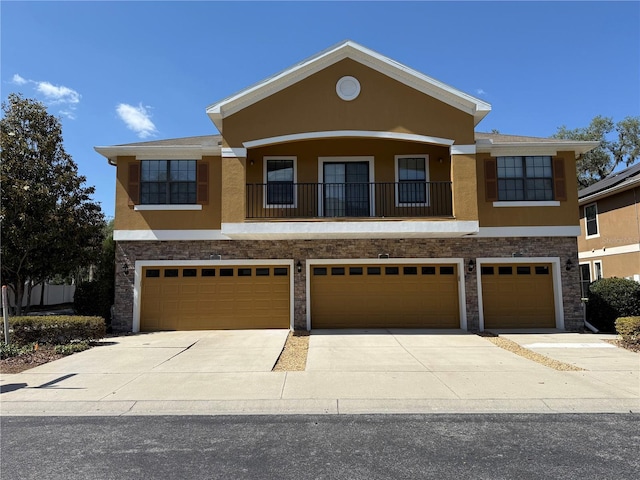 view of front of home with stone siding, a garage, stucco siding, concrete driveway, and a balcony