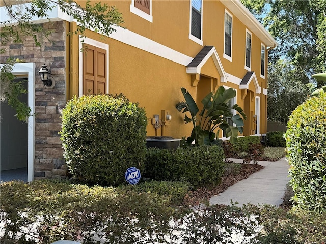 view of side of home with stucco siding and stone siding