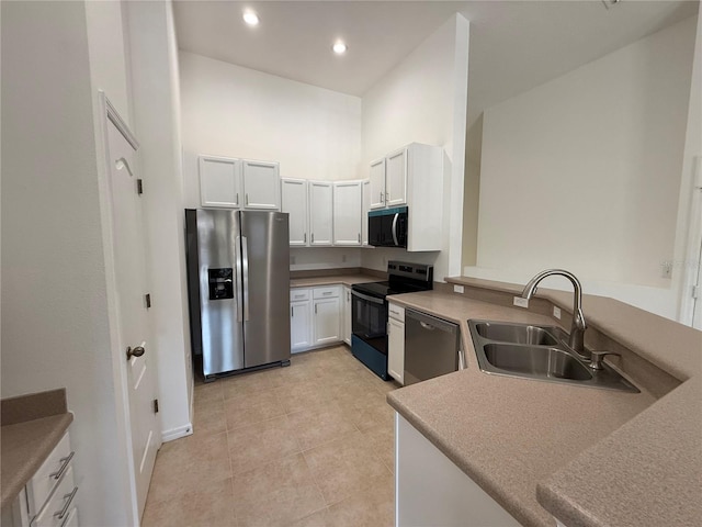 kitchen featuring appliances with stainless steel finishes, a sink, baseboards, light tile patterned floors, and a peninsula