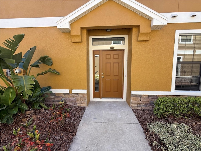 entrance to property featuring stucco siding and stone siding