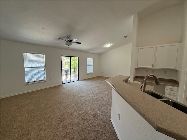 unfurnished living room featuring carpet floors, a sink, baseboards, and ceiling fan