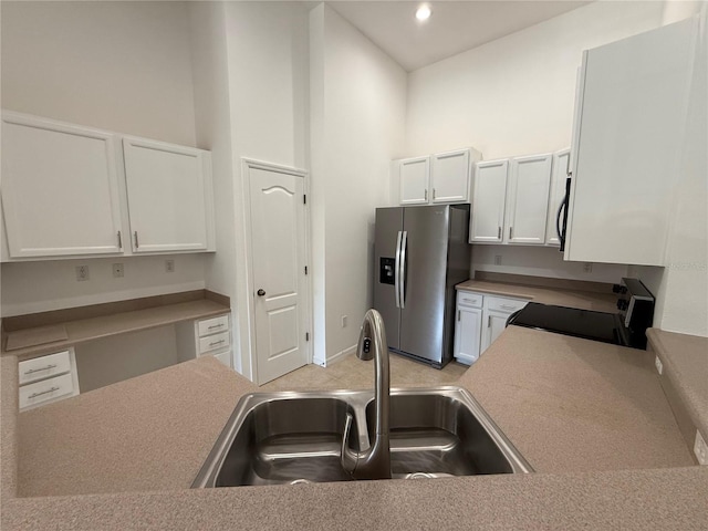 kitchen with a sink, white cabinetry, a towering ceiling, and black appliances