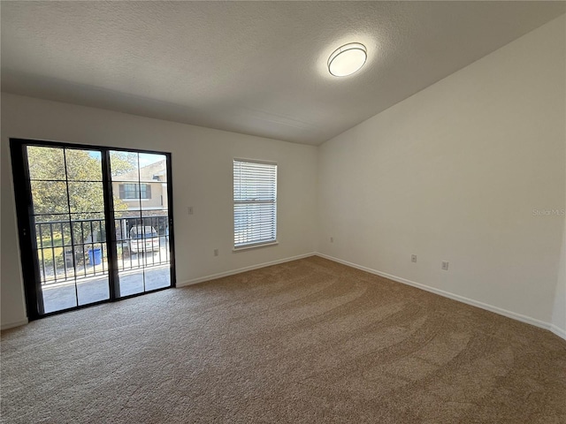 carpeted empty room featuring baseboards, vaulted ceiling, and a textured ceiling