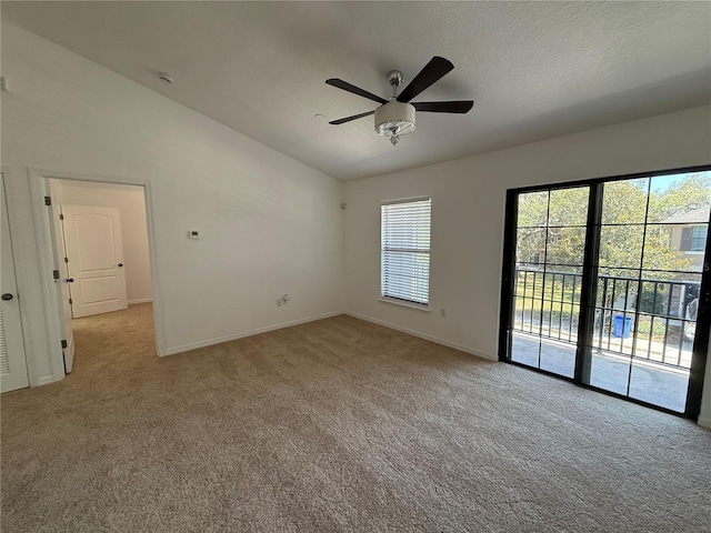 empty room featuring carpet flooring, ceiling fan, vaulted ceiling, and baseboards