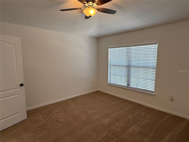 carpeted empty room featuring baseboards and a ceiling fan