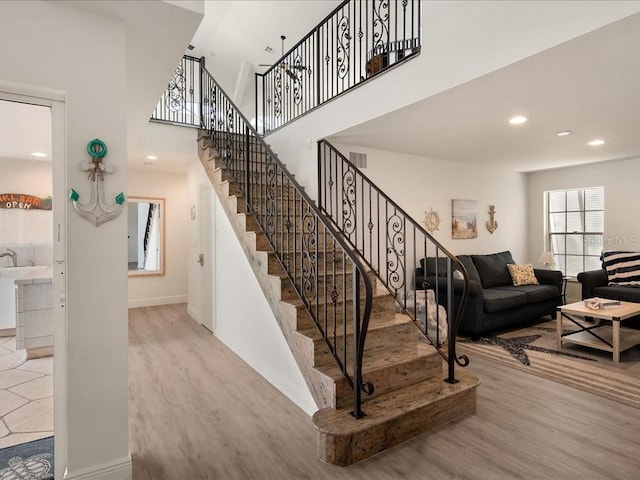 1109 SW 44th St, Cape Coral, FL 33914 - staircase featuring wood finished floors, baseboards, recessed lighting, and a high ceiling